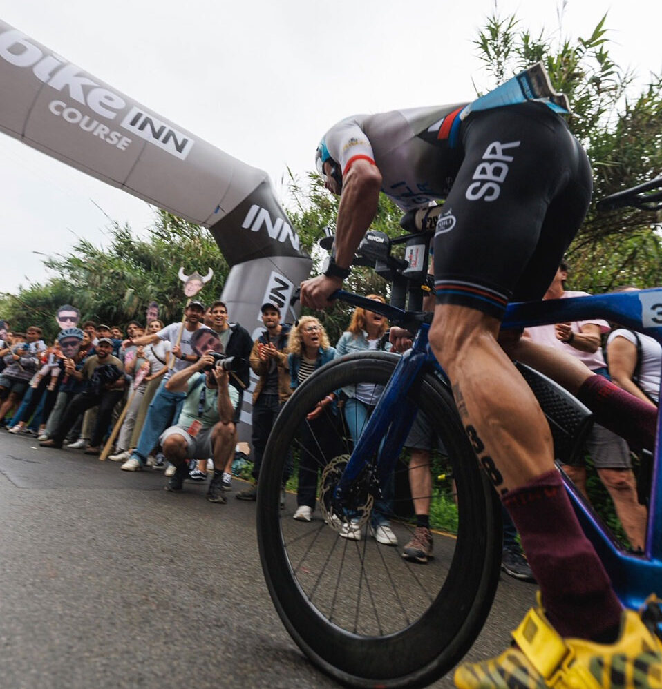Triathlete crossing the finish arch with crowd support during a race