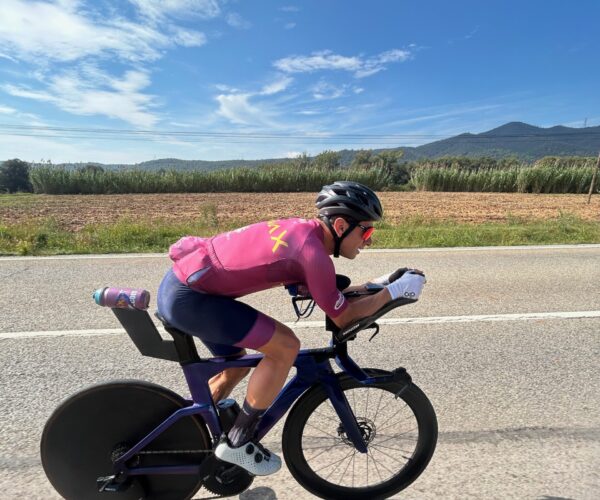 Cyclist in an aero position riding a time trial bike on an open road near Girona