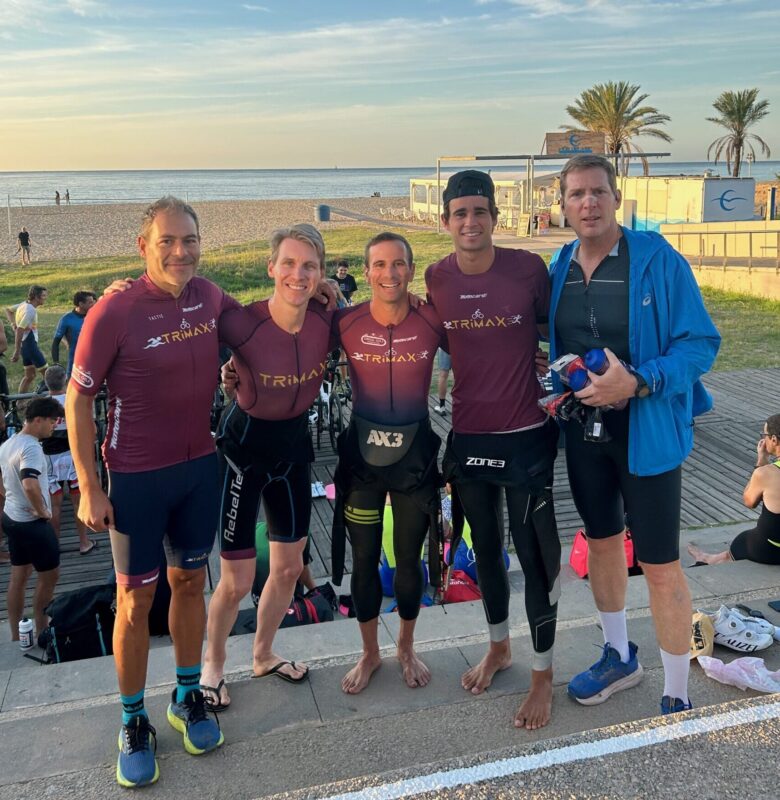 Equipo de triatletas con maillot TRIMAX posando en el paseo marítimo tras entrenar.