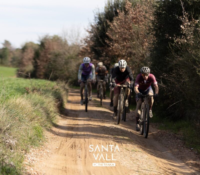 Group of gravel cyclists riding in a line along a countryside track near Girona