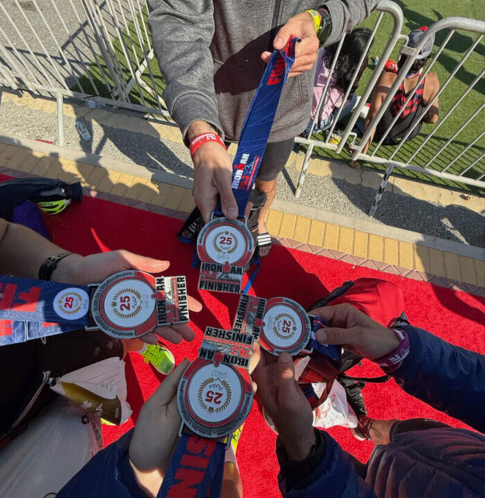 Group of athletes holding their Ironman finisher medals together