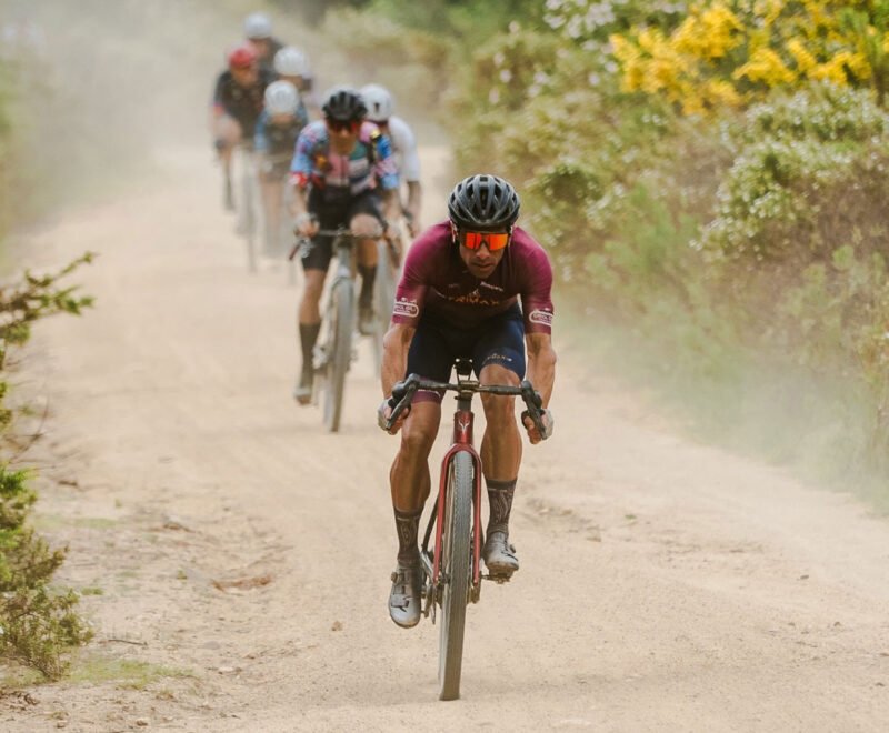 Cyclist riding on a dusty gravel trail in TRIMAX team kit