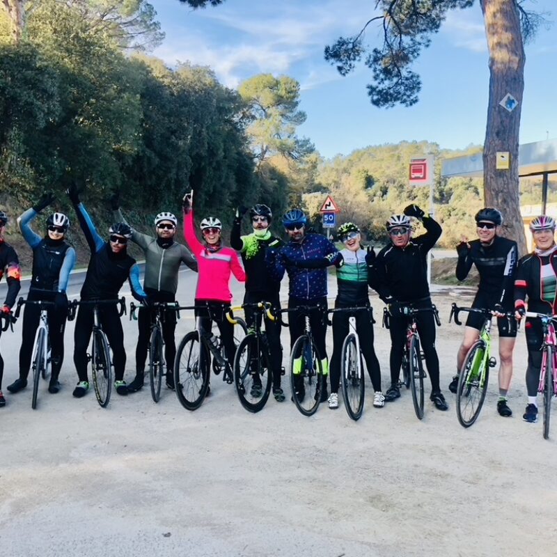 Grupo de ciclistas levantando los brazos en señal de celebración durante una salida.